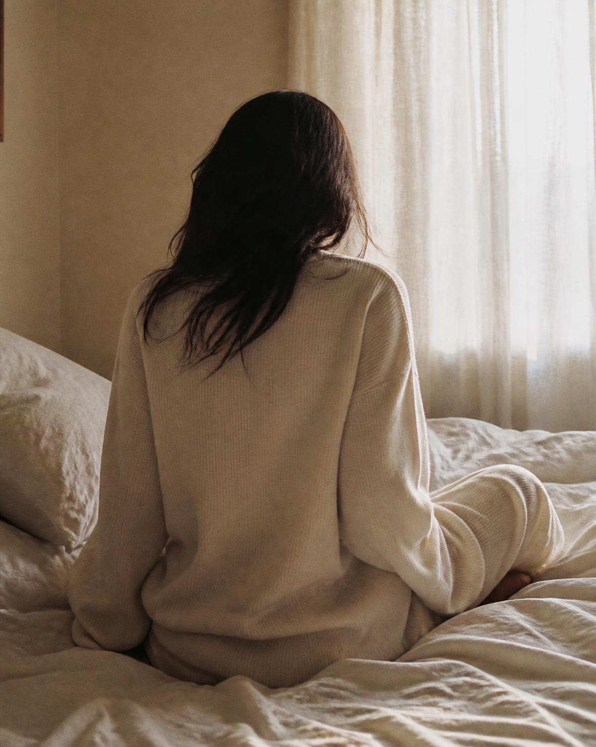Woman in a relaxed cream Solo Body set resting in soft morning light